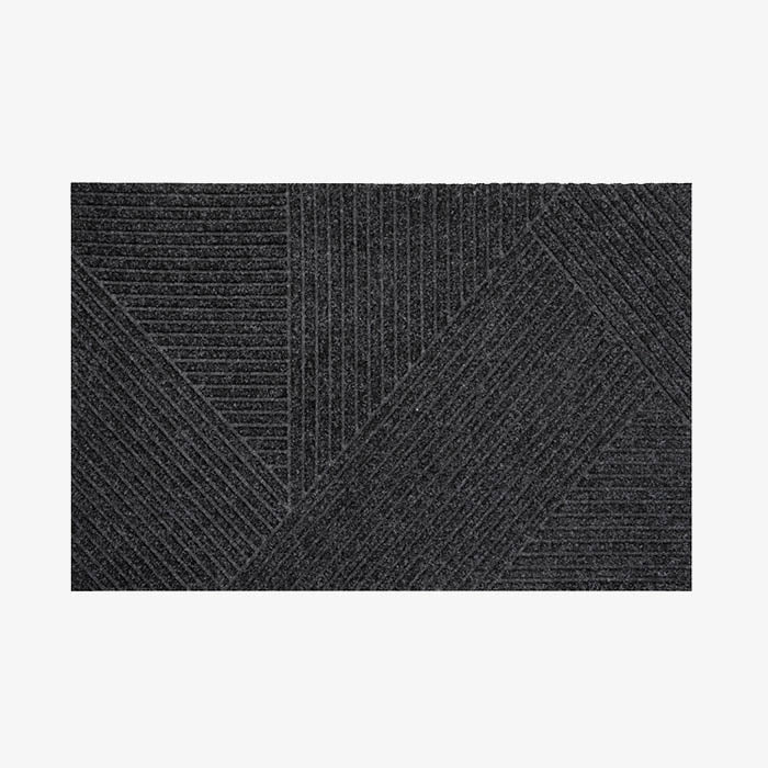 A black doormat with a geometric pyramide design, placed on a white background.