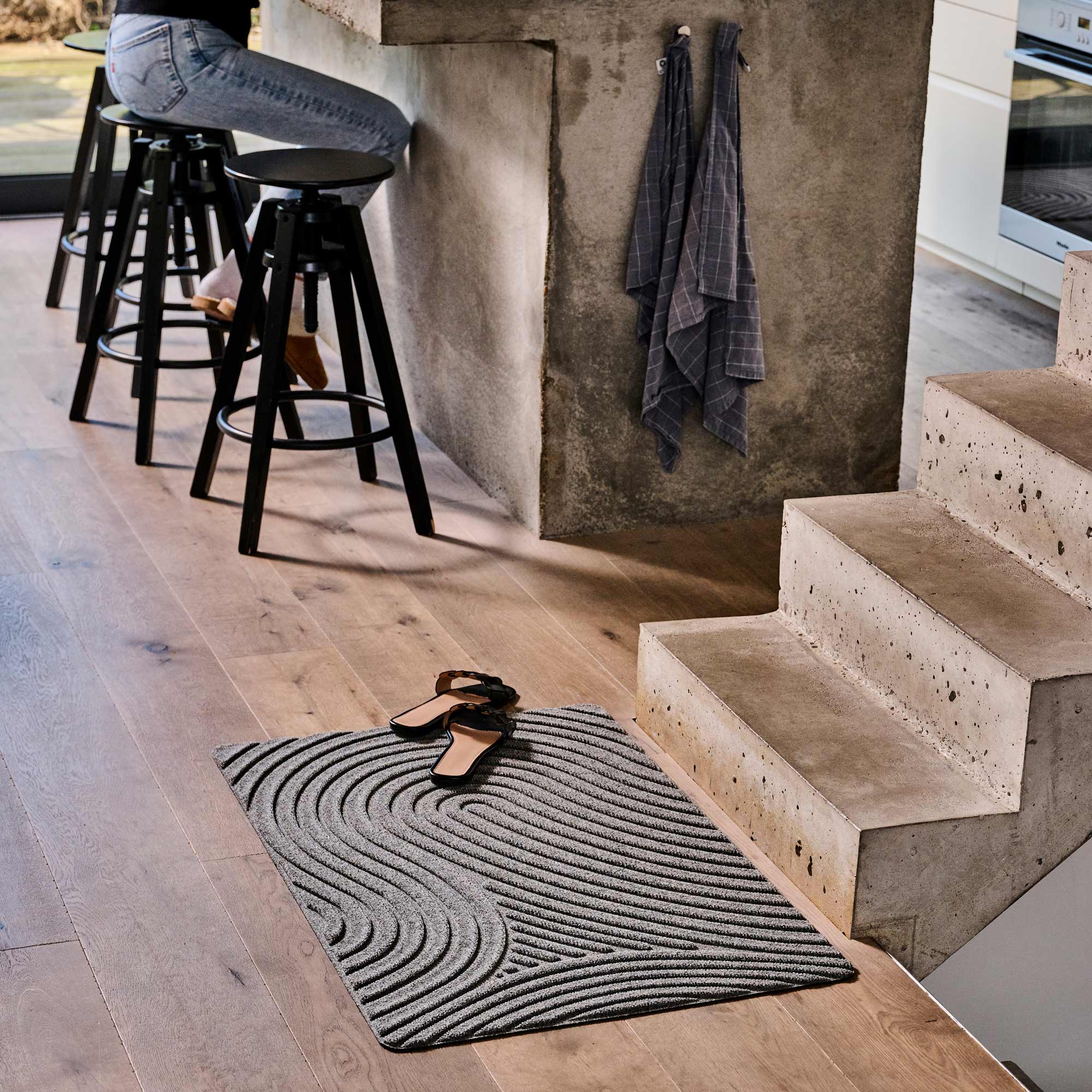 Gray rug with wavy pattern on wooden floor in modern interior setting