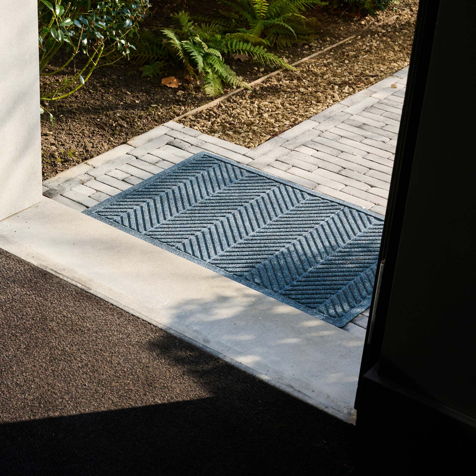 Blue doormat with geometric pattern on a textured surface.