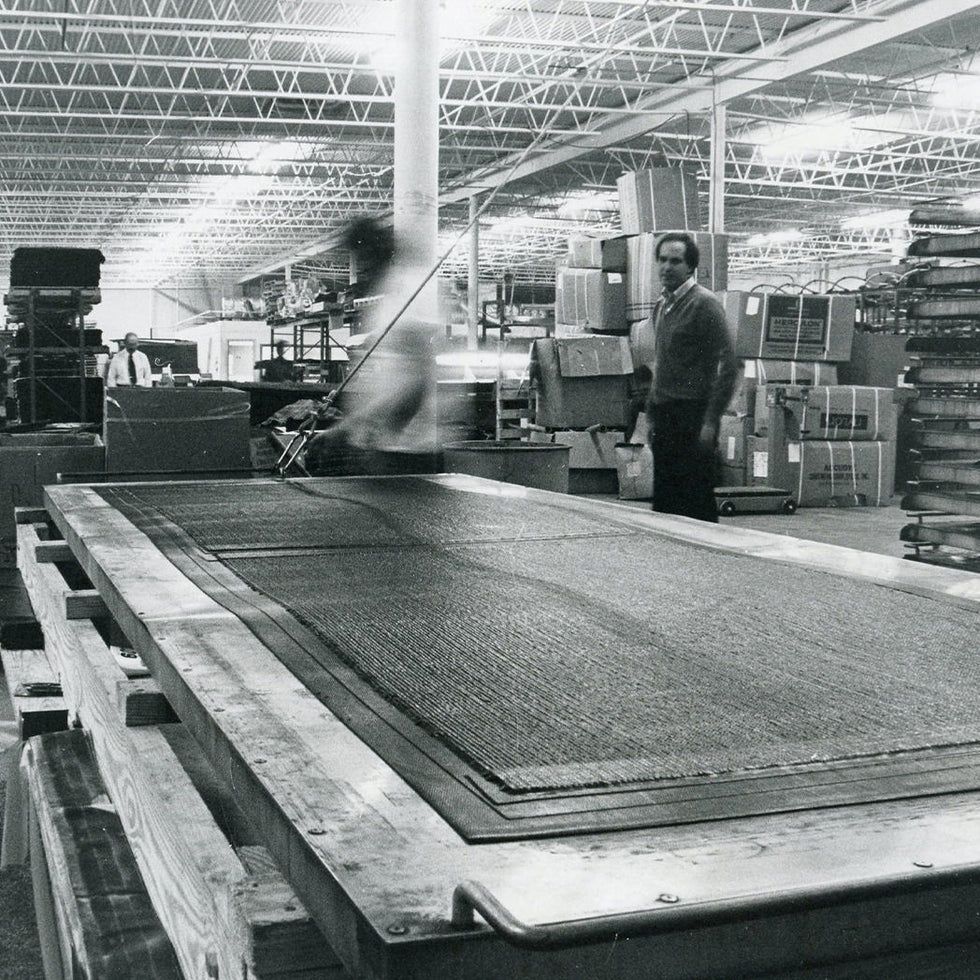 Person working with large mats on a production line in a factory setting