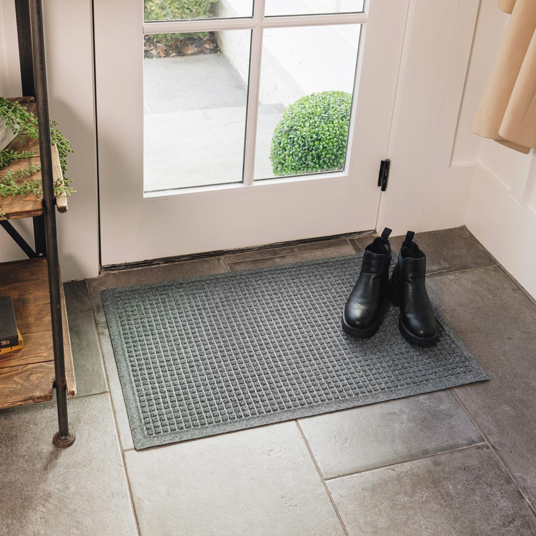 Black boots on a textured doormat at the entrance of a house.