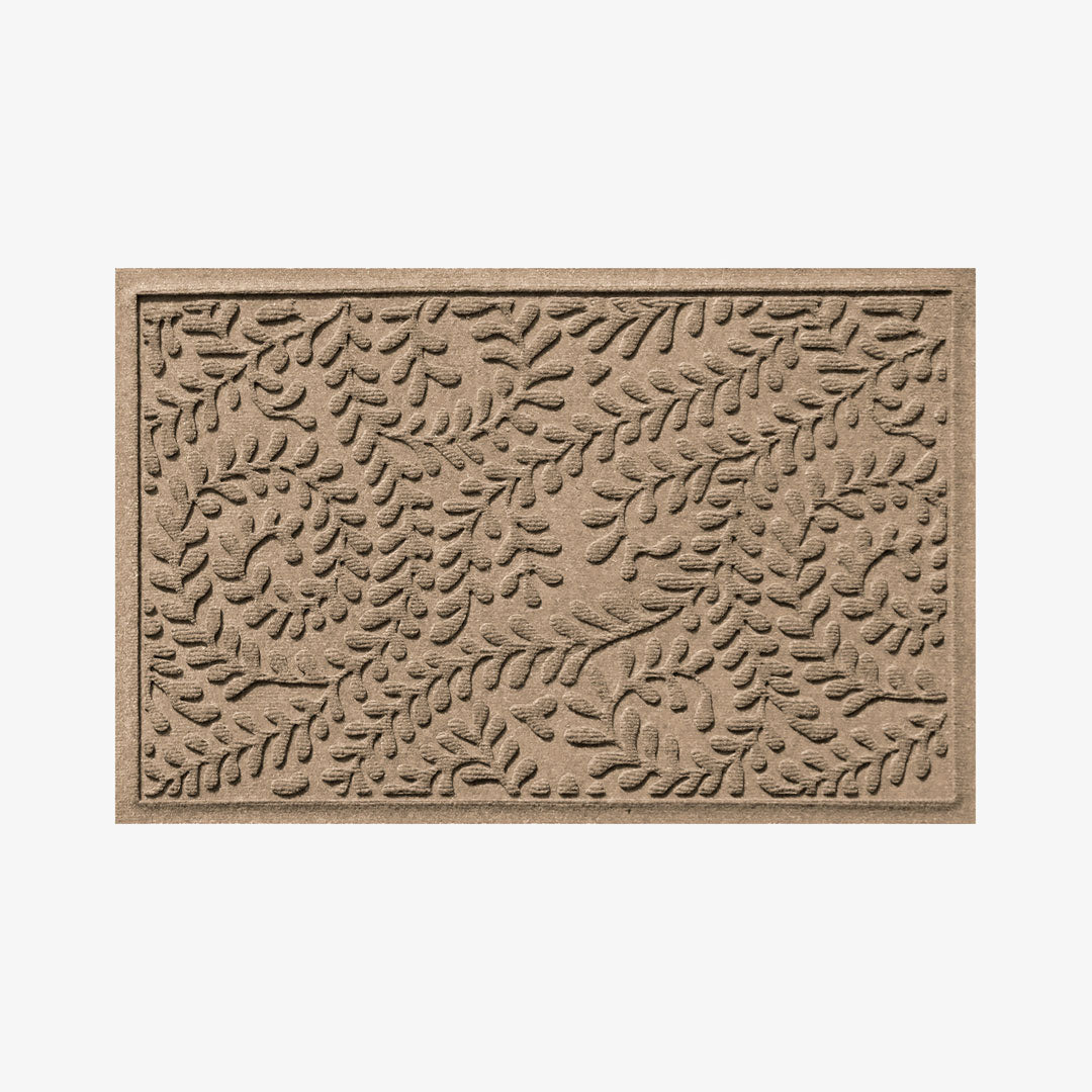 A rectangular, beige indoor/outdoor doormat with a boxwood pattern.