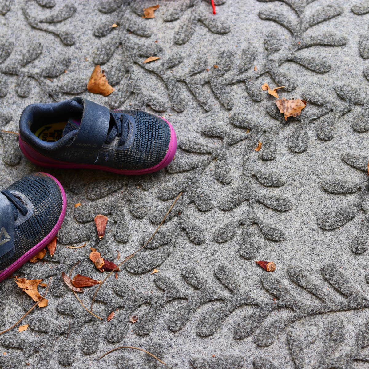 Children's shoes on a textured waterhog mat