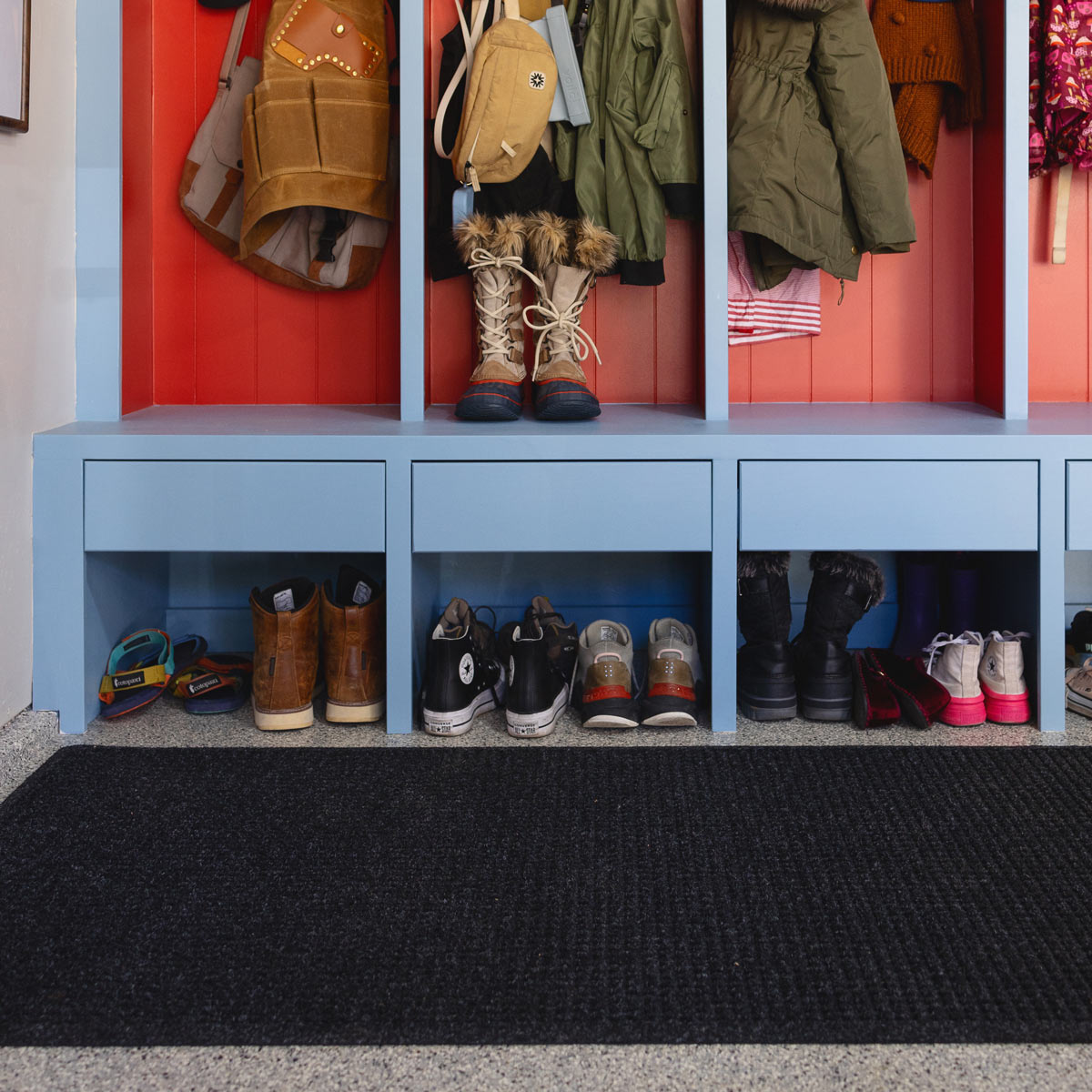 Foyer with coat and shoe storage unit featuring various shoes and coats.