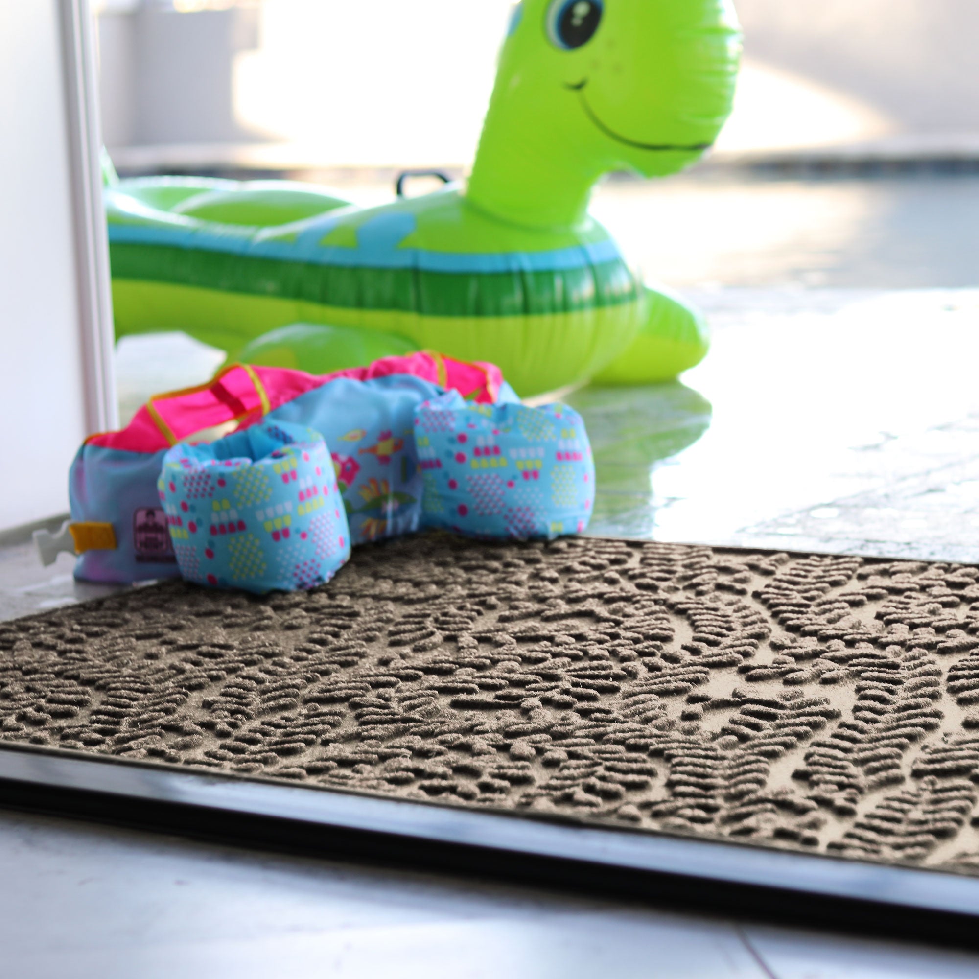 Colorful toy caterpillar on a textured doormat with a green inflatable toy in the background.